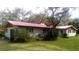 Charming single-story home with red roof and painted white brick nestled in a lush, green landscape at 5540 Cyril Dr, Dade City, FL 33523