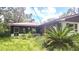 Exterior view of a home with screened-in back porch and lush tropical landscaping around the property at 5540 Cyril Dr, Dade City, FL 33523