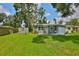 View of a home's backyard with a well-maintained lawn, trees, and a small patio area with outdoor seating at 5840 39Th N St, St Petersburg, FL 33714