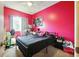 Bedroom with a bed, ceiling fan, and window that allows natural light to illuminate the bright pink walls at 603 Bainbridge Dr, Brandon, FL 33511