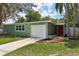 Charming single-story home with an attached garage, green exterior, and a red front door at 607 E River Dr, Temple Terrace, FL 33617