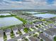 Aerial view of a neighborhood home with a landscaped yard near a lake and surrounded by other houses at 636 Olive Conch St, Ruskin, FL 33570