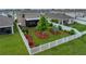 Landscaped backyard with green grass, a white fence, decorative trees, and a covered patio at 636 Olive Conch St, Ruskin, FL 33570