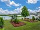 Landscaped backyard featuring decorative plants, a well maintained lawn, and view of community pond at 636 Olive Conch St, Ruskin, FL 33570