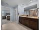 Bathroom with double sinks, wooden cabinets, a shower with a curtain, and access to the main bedroom at 636 Olive Conch St, Ruskin, FL 33570