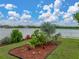 Backyard landscaped flowerbed with decorative lights, and an expansive view of the community pond at 636 Olive Conch St, Ruskin, FL 33570