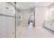 Modern bathroom featuring a glass-enclosed shower, neutral tiling, and bright lighting fixtures at 6879 Talamore Dr, Wesley Chapel, FL 33545