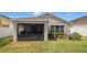 View of the home's back exterior with a screened patio and well manicured lawn at 7120 Forest Mere Dr, Riverview, FL 33578