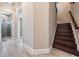 Bright hallway with tile floors leading to staircase with dark wood steps at 7162 Graybrook Dr, Wesley Chapel, FL 33545