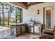 Covered outdoor kitchen with stone counter, built-in grill, and bar seating overlooking the pool at 7162 Graybrook Dr, Wesley Chapel, FL 33545