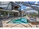 Screened-in pool area featuring an outdoor kitchen, spiral staircase, and a built-in jacuzzi at 7162 Graybrook Dr, Wesley Chapel, FL 33545