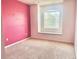 An empty bedroom with pink walls, carpet, and a window with blinds at 824 Lantern Way, Clearwater, FL 33765
