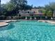 Sparkling community pool surrounded by lounge chairs and lush greenery and the community buildings at 824 Lantern Way, Clearwater, FL 33765