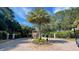 Elegant gated entrance features a central palm tree surrounded by lush greenery and beautiful landscaping at 824 Lantern Way, Clearwater, FL 33765
