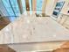 Marble island in a modern kitchen, featuring a cooktop and sleek design, complemented by natural light and custom cabinetry at 824 Lantern Way, Clearwater, FL 33765