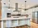 Modern white kitchen featuring stainless steel appliances, a large island, stylish pendant lights, and custom cabinetry at 824 Lantern Way, Clearwater, FL 33765