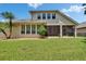 Backyard view of the home with a spacious lawn, mature trees, well-maintained exterior, and screened-in porch at 8704 Winsome Way, Land O Lakes, FL 34637