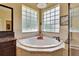 Close up on the bathroom tub surrounded by windows and tile and featuring a tile backsplash at 8704 Winsome Way, Land O Lakes, FL 34637