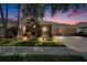 Inviting home exterior with stone accents, a three-car garage, and an illuminated, landscaped yard at dusk at 8704 Winsome Way, Land O Lakes, FL 34637