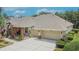 Home exterior featuring a three-car garage, stone accents, and landscaped front yard at 8704 Winsome Way, Land O Lakes, FL 34637