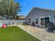 Paver patio in backyard with artificial turf, outdoor seating, and a grill, great for entertaining at 8717 Persea Ct, Trinity, FL 34655