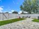 Well-maintained backyard with artificial turf, a paver patio, seating, and a secure white fence at 8717 Persea Ct, Trinity, FL 34655