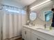 Bright bathroom with a double vanity, modern faucets, and a tub/shower featuring a white shower curtain at 8717 Persea Ct, Trinity, FL 34655