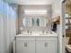 Bathroom boasts double sinks, modern lighting, and a shower with white curtain, creating a functional space at 8717 Persea Ct, Trinity, FL 34655