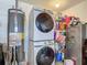Functional laundry area with a stacked washer and dryer, water heater, and shelving for storage at 8717 Persea Ct, Trinity, FL 34655