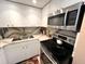 Modern kitchen with white cabinets, stainless steel appliances, and beautiful stone countertops at 880 Mandalay Ave # N311, Clearwater Beach, FL 33767