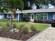 Charming single-story home boasts a vibrant blue exterior with beautiful landscaping and a brick driveway at 906 Ponce De Leon Blvd, Belleair, FL 33756