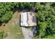 Aerial view reveals a house with a damaged roof surrounded by lush trees at 9910 Jerome Dr, New Port Richey, FL 34654
