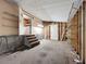 Unfinished basement has shelving, stairs, and access to a laundry area at 9910 Jerome Dr, New Port Richey, FL 34654