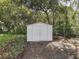 An outdoor white storage shed nestled among lush trees and greenery at 9910 Jerome Dr, New Port Richey, FL 34654