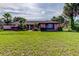 Charming brick home with a well-maintained lawn and mature palm trees under a blue sky at 10365 Lynnhaven Rd, Spring Hill, FL 34608