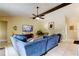 Spacious living room with a large blue sectional sofa, a ceiling fan, and plenty of natural light at 10365 Lynnhaven Rd, Spring Hill, FL 34608