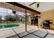 Outdoor entertainment space with a grill, screened in pool with views of a large backyard and wooded area at 10365 Lynnhaven Rd, Spring Hill, FL 34608