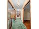 Hallway with green carpet, chandelier, and wood trim at 11159 Cindy Dr, Brooksville, FL 34601