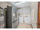 Laundry room featuring white appliances, cabinetry, and a stainless steel fridge at 11159 Cindy Dr, Brooksville, FL 34601