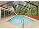 A screened-in pool with a slide and ladder, surrounded by greenery and a brick wall at 11159 Cindy Dr, Brooksville, FL 34601
