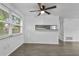 Bright and open living room with a large window, ceiling fan and gray laminate flooring at 1116 Jadewood Ave, Clearwater, FL 33759