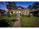 Charming single-story home with a well-manicured lawn, garden beds, and a blue front door at 1119 Highland S St, St Petersburg, FL 33701
