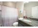 Well-lit bathroom with granite countertop vanity, mirror, and shower with peach-colored curtain at 13821 Moonstone Canyon Dr, Riverview, FL 33579