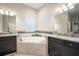 Bright bathroom featuring dual vanity sinks, a central tub with tile surround, and natural light at 13821 Moonstone Canyon Dr, Riverview, FL 33579