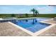 Modern pool with tanning ledge, spa and waterfall feature surrounded by lush landscaping and brick patio at 13821 Moonstone Canyon Dr, Riverview, FL 33579