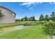 Backyard featuring a green lawn and small pond bordered with tall trees and bright sky at 13905 Abbey Ln, Largo, FL 33771