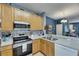 Kitchen featuring stainless steel appliances, tile backsplash, and light wood cabinets at 13905 Abbey Ln, Largo, FL 33771
