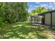 Green backyard with mature shade trees and screened-in pool with connected patio at 1402 E Mimosa Dr, Plant City, FL 33563