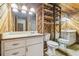 Rustic bathroom featuring wood paneling, a vanity, toilet, mirror, and wooden shelves adding character to the space at 1402 E Mimosa Dr, Plant City, FL 33563