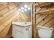 Rustic bathroom showcasing wood paneling, a vanity, a mirror, and a toilet adding charm to the space at 1402 E Mimosa Dr, Plant City, FL 33563